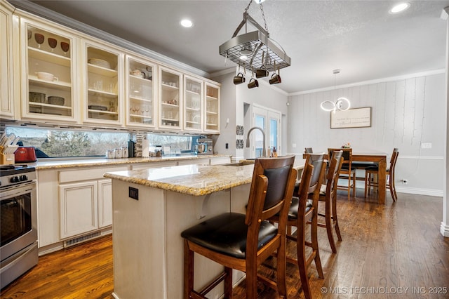 kitchen featuring crown molding, a sink, stainless steel gas range oven, and cream cabinets