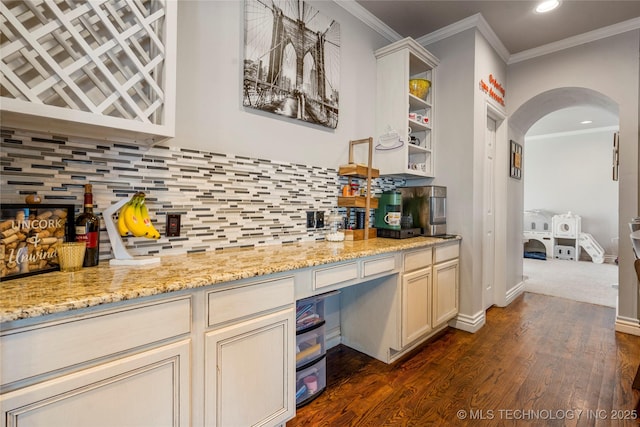 bar with arched walkways, dark wood-type flooring, backsplash, and ornamental molding