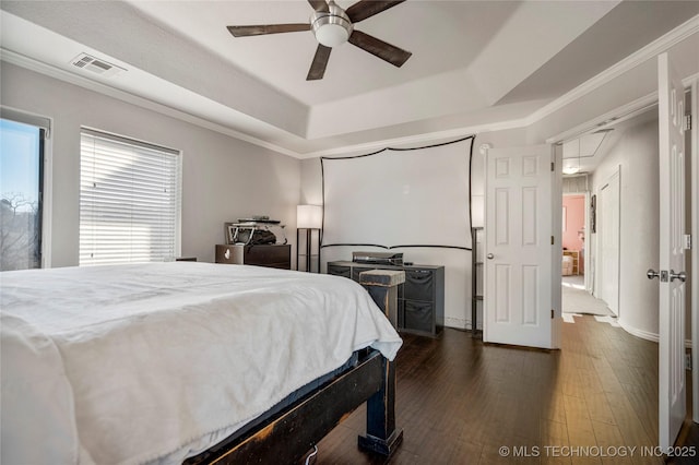 bedroom featuring attic access, visible vents, a raised ceiling, ornamental molding, and dark wood-style flooring