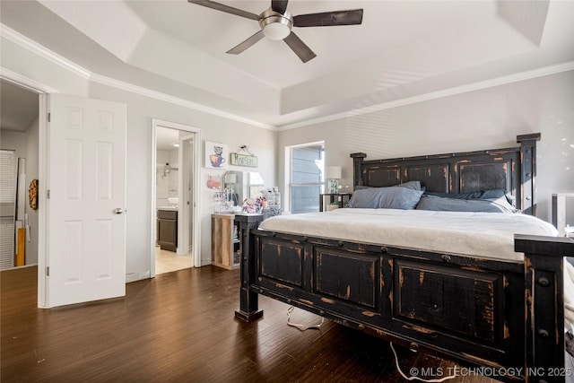 bedroom featuring ceiling fan, dark wood-style flooring, ornamental molding, a raised ceiling, and ensuite bath