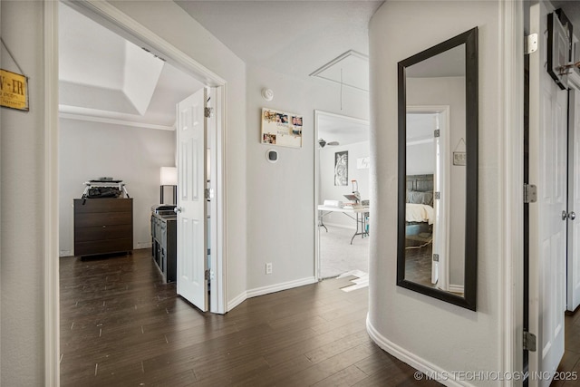 hallway featuring attic access, dark wood-style flooring, and baseboards