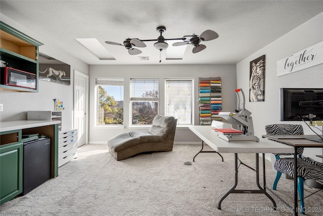 carpeted office with a textured ceiling, ceiling fan, visible vents, and baseboards