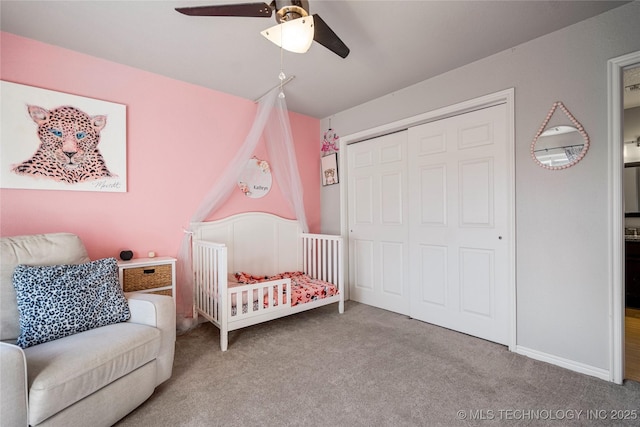 bedroom with baseboards, a ceiling fan, carpet flooring, a nursery area, and a closet