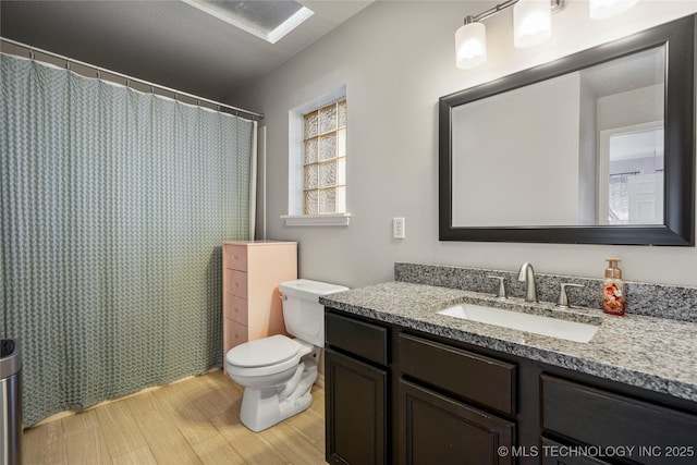 full bath with toilet, wood finished floors, and vanity