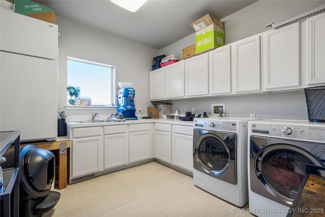 washroom with a sink, cabinet space, and washer and dryer