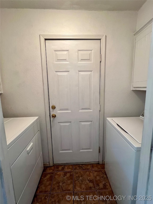 laundry room featuring dark tile patterned floors, cabinet space, and separate washer and dryer