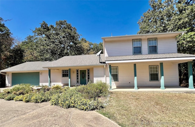 traditional home featuring a front lawn, roof with shingles, a porch, and an attached garage