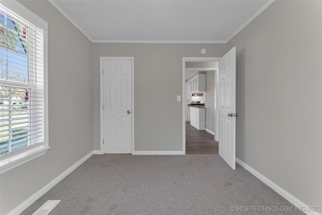 unfurnished bedroom with carpet flooring, crown molding, and baseboards