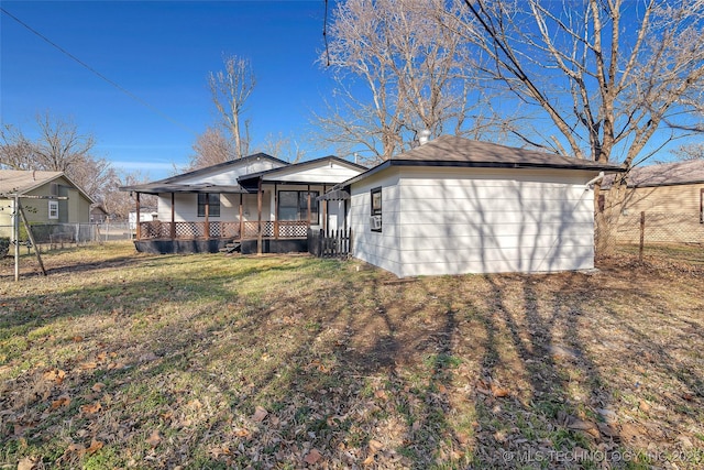 rear view of house featuring fence and a lawn