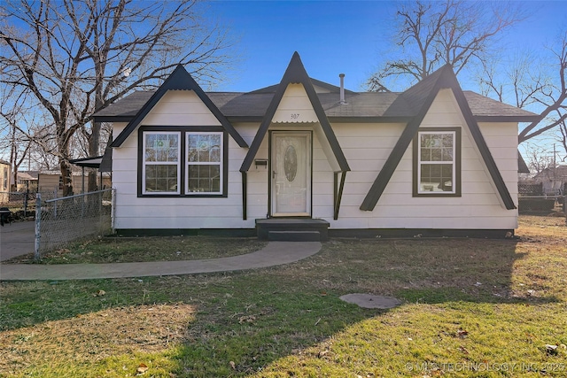 tudor-style house featuring fence and a front lawn