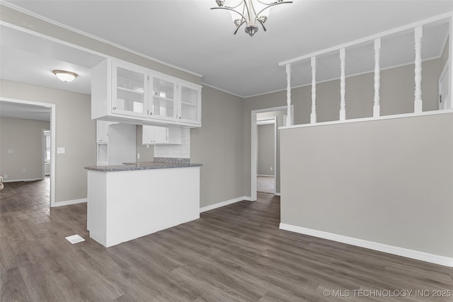 kitchen featuring baseboards, dark wood finished floors, glass insert cabinets, white cabinetry, and backsplash