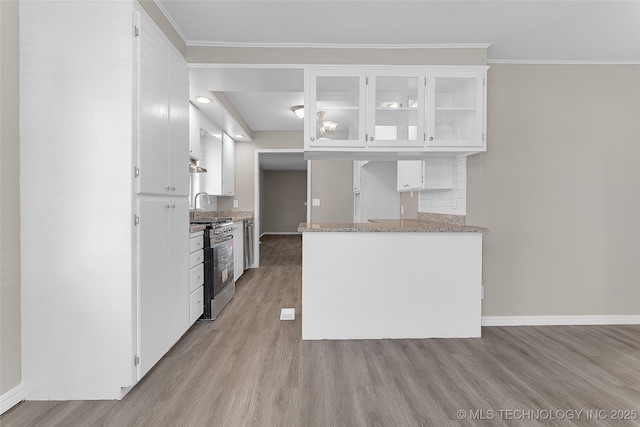 kitchen with light wood-style floors, white cabinetry, glass insert cabinets, and stainless steel gas range oven