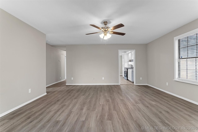 empty room featuring ceiling fan, wood finished floors, and baseboards