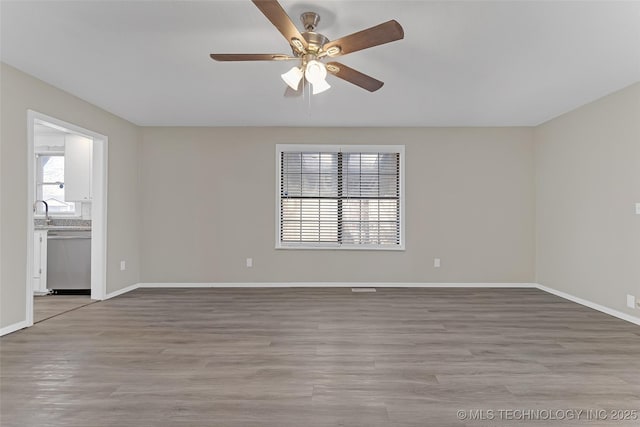 unfurnished room featuring light wood-style floors, baseboards, and a ceiling fan