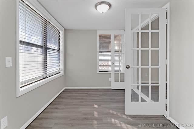 unfurnished room with french doors, plenty of natural light, baseboards, and wood finished floors