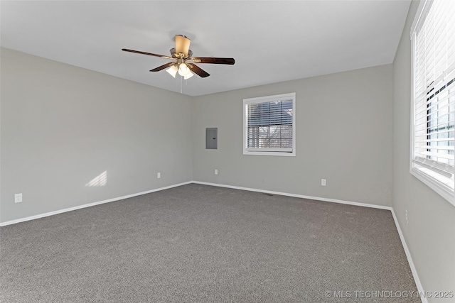 spare room with a ceiling fan, electric panel, dark carpet, and baseboards