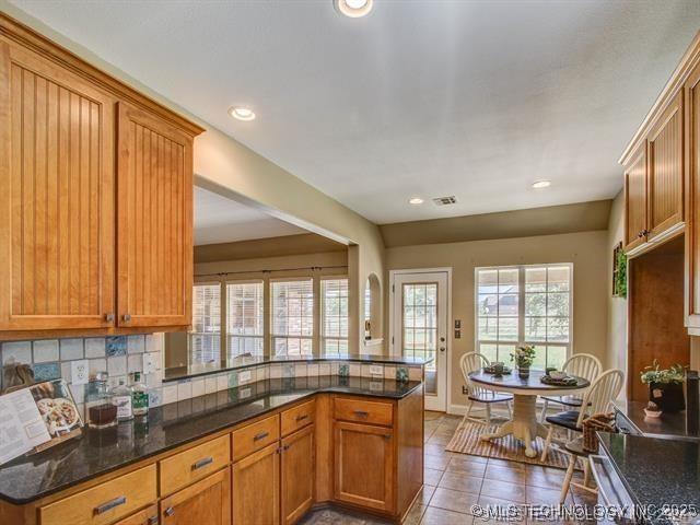 kitchen featuring brown cabinets, a healthy amount of sunlight, tile patterned floors, and decorative backsplash