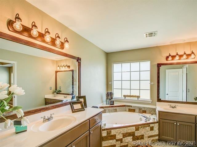 bathroom with a bath, visible vents, two vanities, and a sink