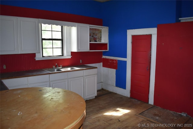 kitchen with light wood-style floors, white cabinets, and a sink