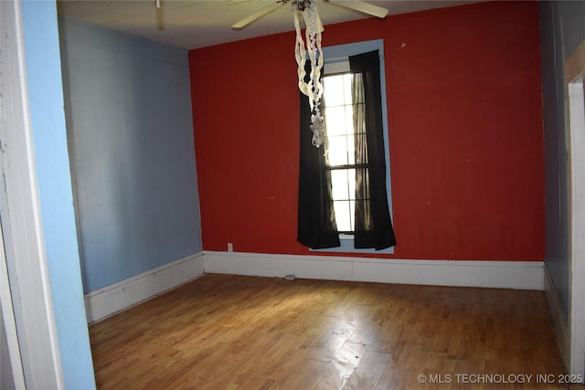 unfurnished room featuring a ceiling fan, baseboards, and wood finished floors