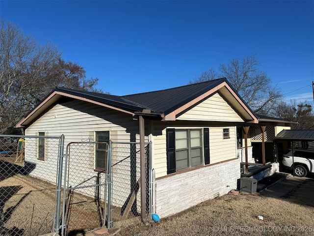 view of side of property featuring a gate, fence, and metal roof