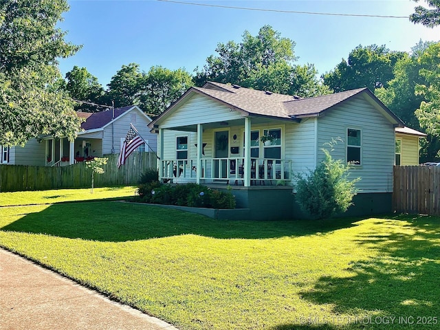 ranch-style house with a porch, a front yard, roof with shingles, and fence