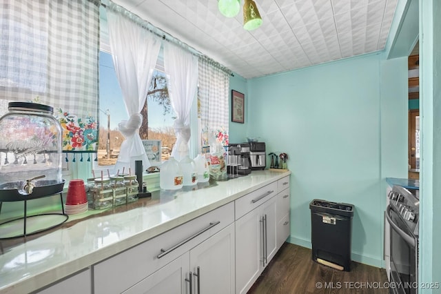 kitchen featuring baseboards, stainless steel electric range oven, light countertops, white cabinetry, and dark wood-style flooring