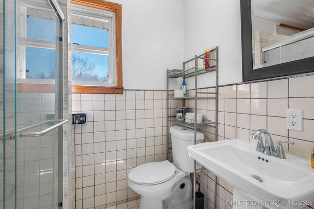 full bathroom featuring tile walls, toilet, tiled shower, and a sink
