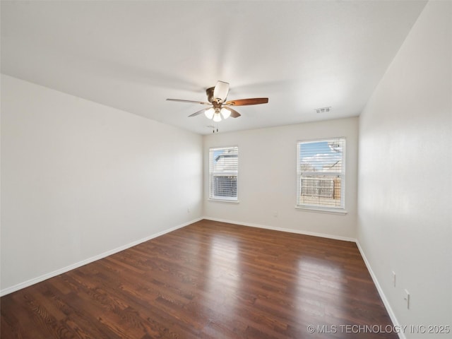 empty room with a ceiling fan, visible vents, baseboards, and wood finished floors