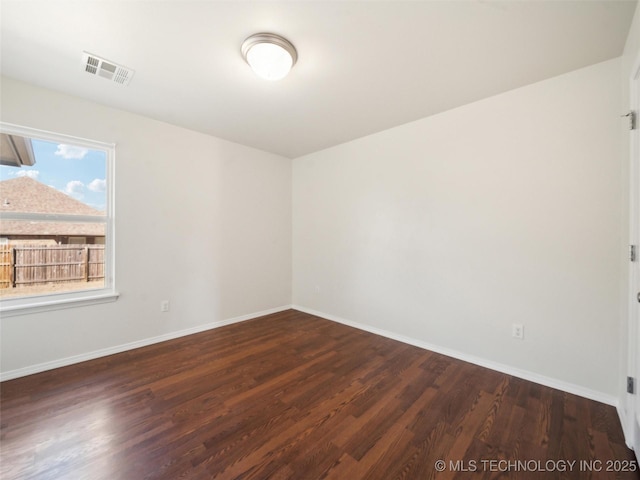 empty room featuring baseboards, visible vents, and wood finished floors