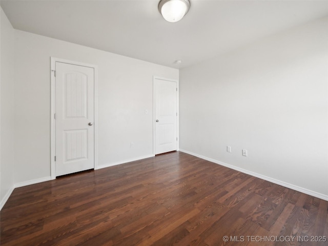 unfurnished bedroom featuring dark wood-type flooring and baseboards