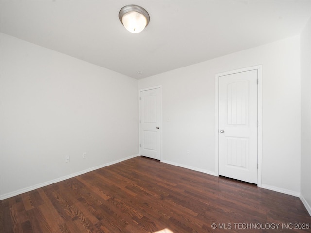 spare room with baseboards and wood finished floors