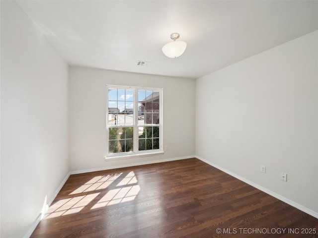 empty room with visible vents, baseboards, and wood finished floors