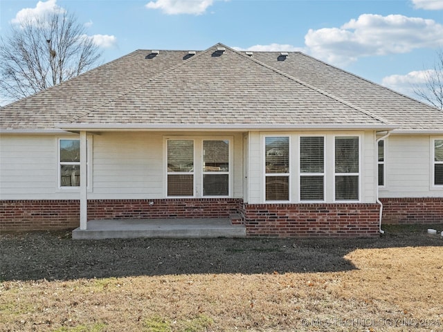 rear view of property with a patio, brick siding, and roof with shingles