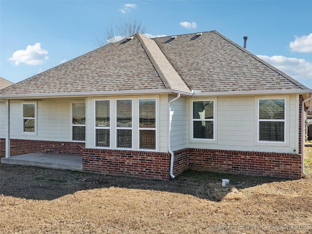 view of home's exterior with brick siding, roof with shingles, and a patio area