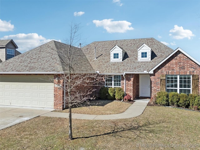 new england style home featuring brick siding, roof with shingles, an attached garage, driveway, and a front lawn