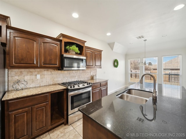 kitchen with stainless steel appliances, visible vents, decorative backsplash, a sink, and dark stone countertops