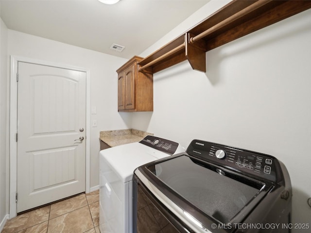 laundry room featuring cabinet space, light tile patterned floors, baseboards, visible vents, and independent washer and dryer