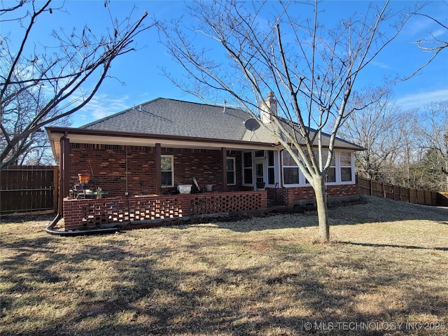 rear view of house with brick siding, a chimney, and fence