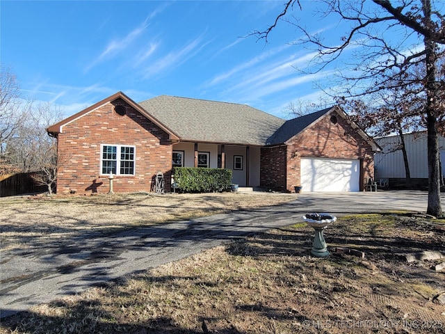 single story home with an attached garage, a shingled roof, aphalt driveway, and brick siding