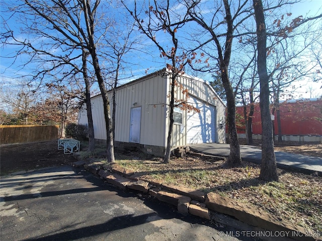 view of outdoor structure with driveway, fence, and an outdoor structure