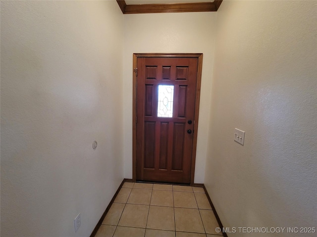 doorway with ornamental molding, baseboards, and light tile patterned floors