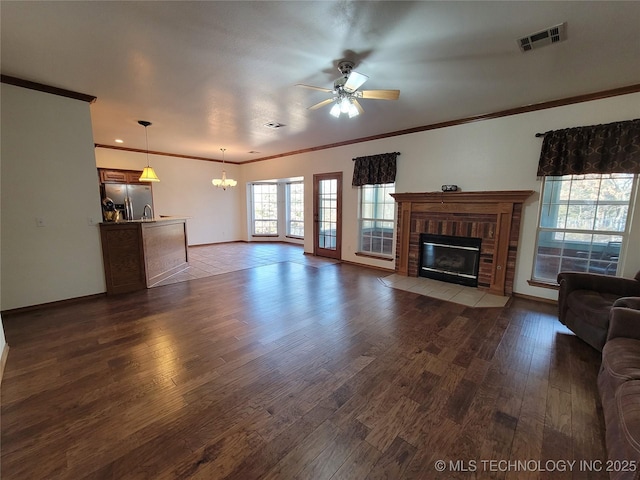 unfurnished living room featuring a fireplace, dark wood finished floors, visible vents, and crown molding