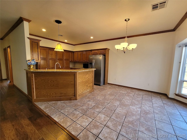 kitchen with a peninsula, visible vents, baseboards, stainless steel fridge with ice dispenser, and an inviting chandelier