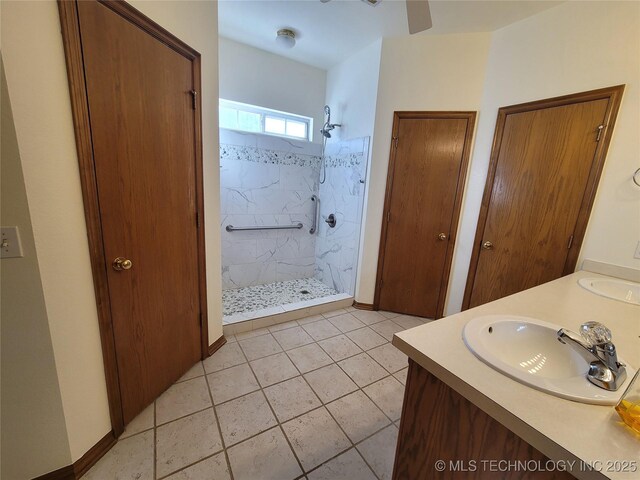 bathroom with double vanity, a marble finish shower, baseboards, and a sink