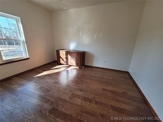 spare room with baseboards and wood finished floors