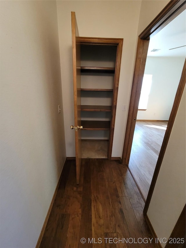 hallway with visible vents, dark wood finished floors, and baseboards