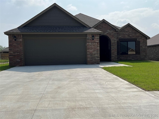 view of front of house with brick siding, roof with shingles, an attached garage, a front yard, and driveway