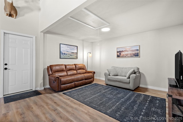 living room featuring attic access, baseboards, and wood finished floors