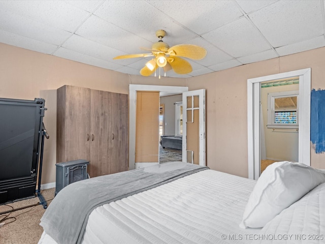 bedroom with carpet floors, a drop ceiling, a ceiling fan, and baseboards